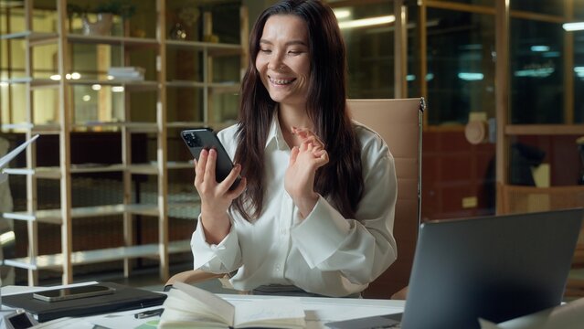 Happy smiling Asian woman Chinese businesswoman architect business employer texting mobile phone message scrolling social media addict Korean Japanese female girl user smartphone online work in office - Powered by Adobe