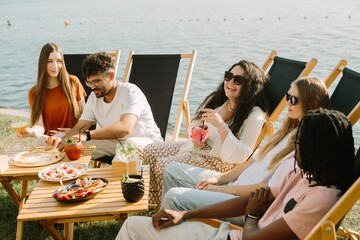 Friends enjoying drinks and food by the lake