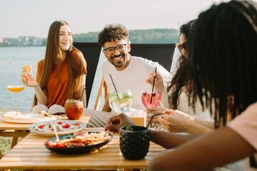 Friends enjoying drinks and food by the lake