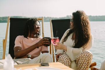 Friends toasting drinks at a lakeside cafe