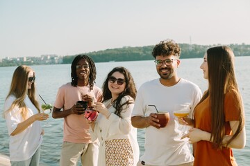 Cheerful friends enjoying drinks by the lake