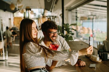 Young couple taking a selfie while enjoying drinks at a cafe