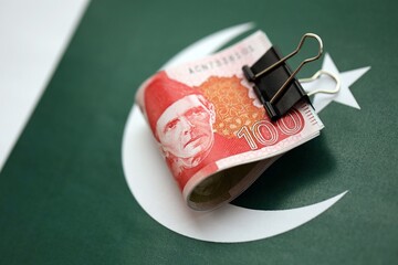 Pakistan rupees banknotes on Pakistani flag. The current Pakistan money bills