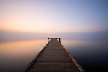Obraz premium Pier Stretching into a Misty Sunset Landscape