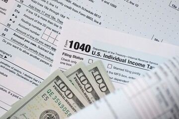 Hundred dollar bills and 1040 individual income tax return form blank close up