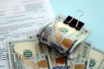 Fototapeta premium Big amount of United States dollar bills on table with 1040 tax return form