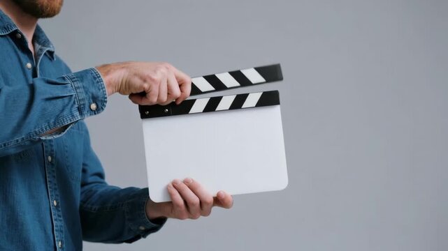 A person's hands using a blank white clapperboard to mark the start of a scene, a classic symbol of filmmaking, video production, cinema, and the movie entertainment industry