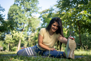 Smiling beautiful fit woman stretching legs outdoors in park, athletic female warming up during morning workout in fresh air