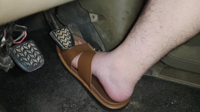 The detailed scene of feet wearing brown sandals stepping on the pedals inside the car interior emphasizes driving safety and consideration of foot position.