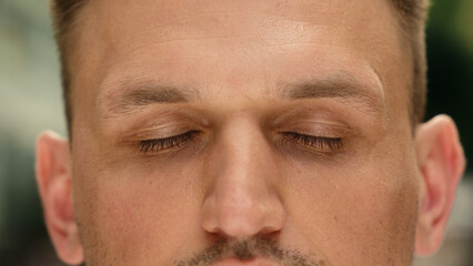 Obraz premium Eyes close up closed human Caucasian man cropped view eyesight guy close eye outdoors clear vision health laser correction medicine gaze blink face skin care male calm serene portrait in city outside