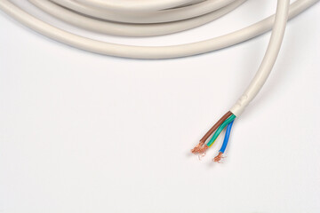 A wide-angle shot on a neutral background shows a coiled white electrical cable with its end...