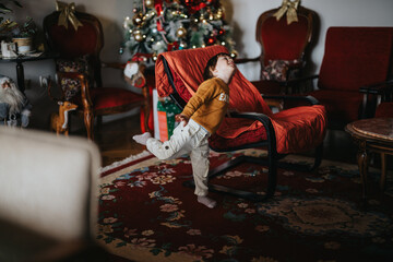 A young boy enjoying himself in a warmly decorated home. A Christmas tree glows in the background,...