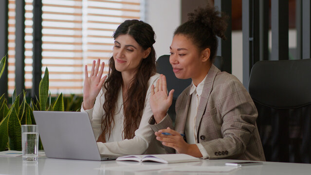 Multiracial girls African American Caucasian business women female friendly smiling colleagues multiethnic businesswomen partners online meet laptop video call conference greet chat office negotiation