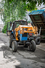 Fototapeta premium Construction vehicle in action at a busy site under leafy trees during the day