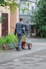 Workers tending to community garden in urban setting while pushing wheelbarrow on sunny day