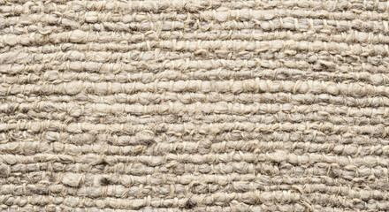 Close up of a woven beige fabric texture with horizontal lines and a rough surface appearance showing detail