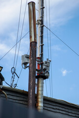 Communication tower rises above a rustic rooftop under a clear blue sky in the early morning light