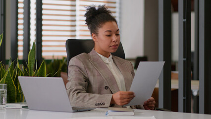 African American business woman female boss office agent read document financial report ethnic girl...