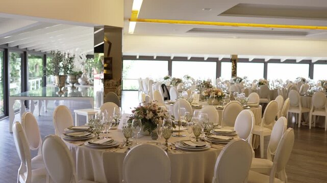 luxury banquet room prepared for wedding with round tables and flowers