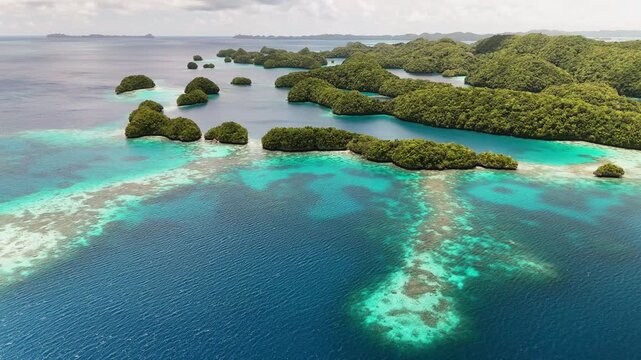 Aerial cinematic sequence orbiting to reveal the crystal blue waters and islands surrounding Palau. Wide panning drone shot