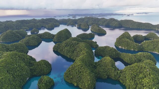 Sweeping drone shot gliding around the sparkling marine blue ocean and scattered green islands within Palau&rsquo;s archipelago. Wide revealing drone shot.