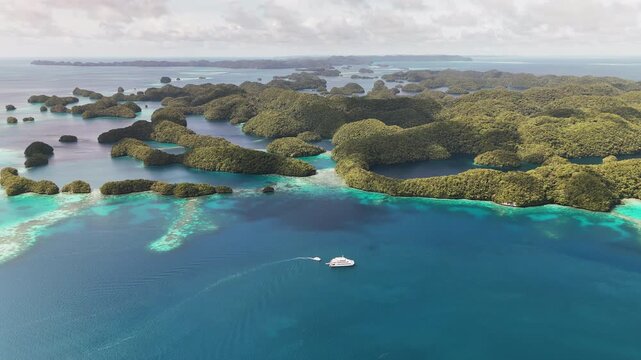 Stunning drone footage sweeping across the electric-blue seas and untouched islands in Palau. Wide shot of boats in the lagoon.