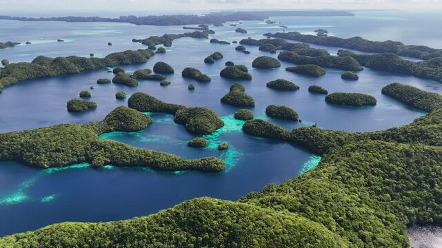 Aerial cinematic sequence scanning and revealing the rich ocean blues and forested island clusters of Palau. Wide cinematic aerial drone shot