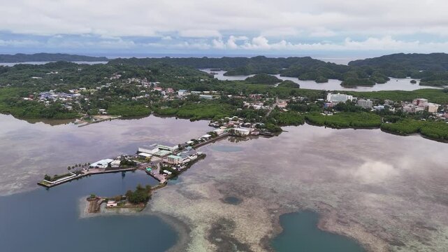 High-quality drone shot scanning and revealing the vivid aqua ocean and green-covered terrain in Palau. Circling drone shot of an island resort.