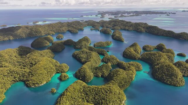 Aerial cinematic sequence showcasing and revealing the serene turquoise coastline and small tropical islands around Palau. Wide revealing drone shot.