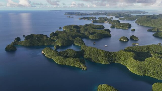 Breathtaking drone view revealing the rich ocean blues and forested island clusters in Palau. Wide revealing drone shot.