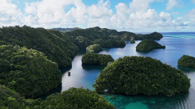 Sweeping drone shot revealing the glowing waters, hidden lagoons, and emerald islands in Palau. Wide revealing aerial drone shot.
