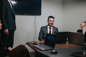 A team of professionals engages in a business meeting, featuring laptops at a modern workspace....