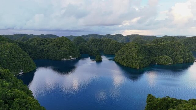 Breathtaking drone view gliding around the serene turquoise coastline and small tropical islands of Palau. Wide cinematic revealing drone shot.