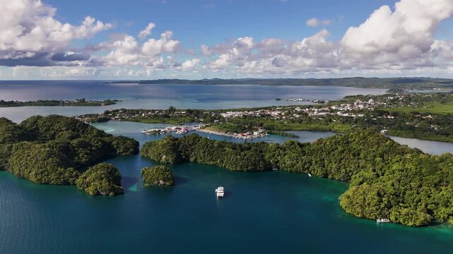 Aerial cinematic sequence circling and revealing the clear tropical waters and exotic landforms of Palau. Wide shot of resort and yacht.