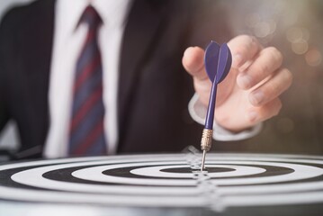 Businessman aiming dart at target for business success and goal achievement