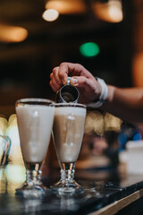 Barista skillfully pours milk to create coffee beverages in tall glass cups, showcasing preparation techniques. Scene features attention to detail, and a focus on craftsmanship and beverage aesthetics