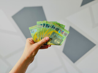 Hand holding stack of currency banknotes against abstract background  