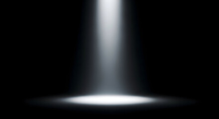 A beam of white light shining down from above onto a dark surface in a studio setting backdrop shot