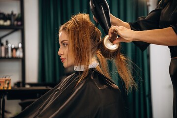 Drying the hair. Woman is in a beauty salon with hair stylist