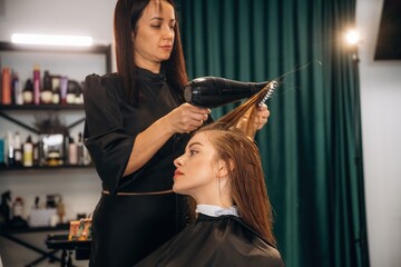 Drying the hair. Woman is in a beauty salon with hair stylist