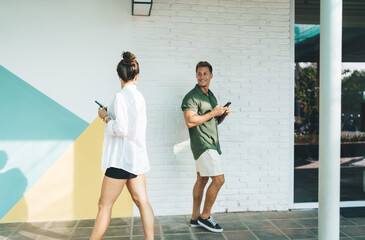 Freelance duo walking side by side with smartphones, immersed in individual tasks while staying...