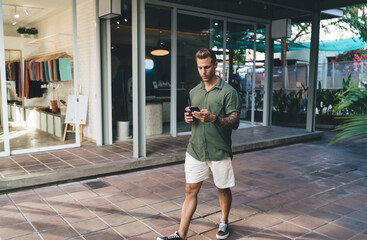 Man sipping smoothie while scrolling phone—demonstrates relaxed mobile consumption, app browsing...