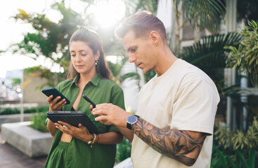 Man and woman smiling and using smartphones together outdoors, sharing digital joy and seamless...