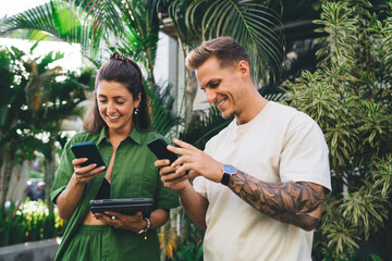 Young woman signing on digital tablet while man watches attentively, illustrating modern teamwork,...