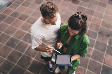 Smiling couple looking up while working on tablet, holding stylus, conveying joy, openness, and...