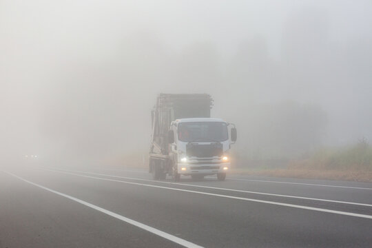 skip bin truck travelling on highway road through fog with low visibility