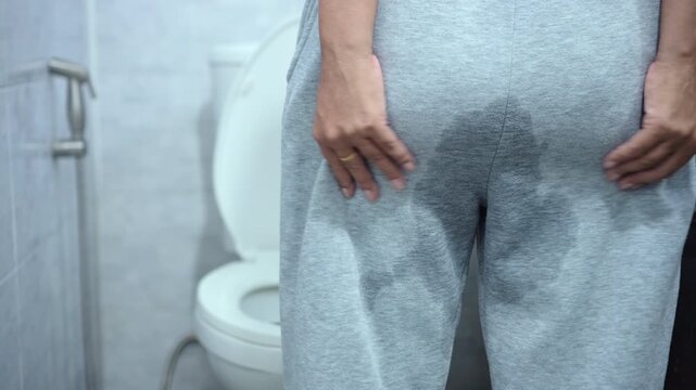 close-up back view of an elderly woman with wet pants, showing pee leak from stress urinary incontinence and weak bladder problems in older age