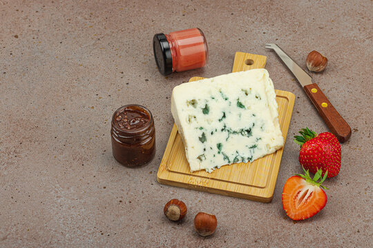 Cheese assortment on wooden boards with strawberries, nuts and jam on stone background