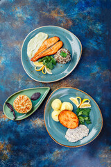 Several dishes of chicken, fish, potatoes, various salads and sauces.