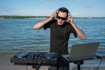 Caucasian man works as a DJ on the beach. 